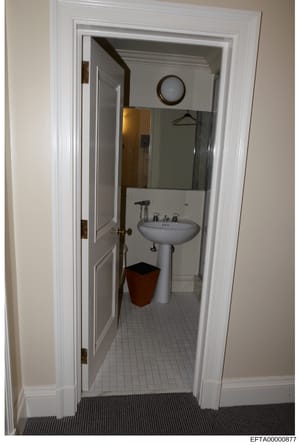 This is an evidence photograph of a bathroom interior, showing a pedestal sink, mirror, shower enclosure, and basic furnishings. The image appears to be documentation of a property space, likely taken during the investigation of an Epstein-linked res