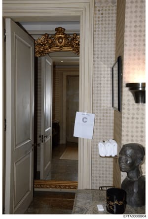 This is a photograph of an elegant residential hallway interior, showing ornate architectural details including a decorative gold-leaf pediment above the doorway, diamond-patterned wallpaper, and classical décor. An evidence marker labeled 'C' is vis