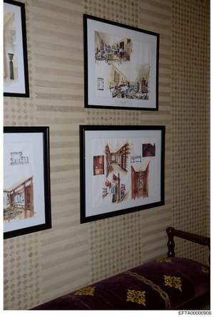 This photograph documents framed architectural renderings and interior design sketches displayed on a patterned wall. The sketches appear to be professional design plans for residential spaces, showing room layouts, furniture arrangements, and archit