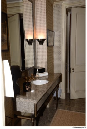 This is a photograph of a luxuriously appointed bathroom, likely from one of Jeffrey Epstein's properties. The image shows an upscale vanity setup with dual sinks, granite countertops, decorative lighting fixtures, and high-end finishes. The photo se