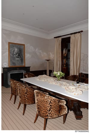 This is a professional photograph of an elegantly appointed dining room, likely from one of Jeffrey Epstein's properties. The room features a long white dining table, leopard print upholstered chairs, a black fireplace with decorative artwork, cream-
