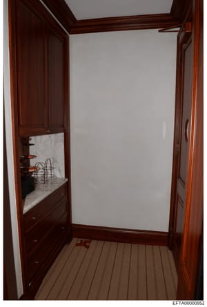 This is an evidence photograph from the Epstein investigation files showing the interior of a closet or dressing room with custom dark wood cabinetry, marble countertop surfaces, and integrated storage fixtures. The photograph documents the interior 