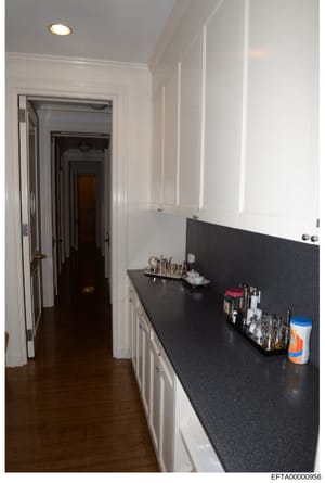 This is an evidence photograph showing the interior of a bathroom or dressing room space, featuring a vanity counter with black countertop, white cabinetry, and various personal items and toiletries. The image appears to be part of property documenta