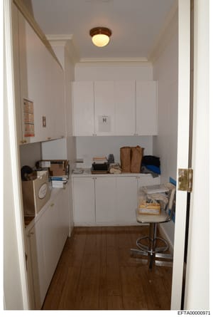 This is a photograph of a narrow utility or laundry room showing white cabinetry, a washer/dryer unit on the left side, open shelving with various household items and bags, and hardwood flooring. The image appears to be documentation of property inte