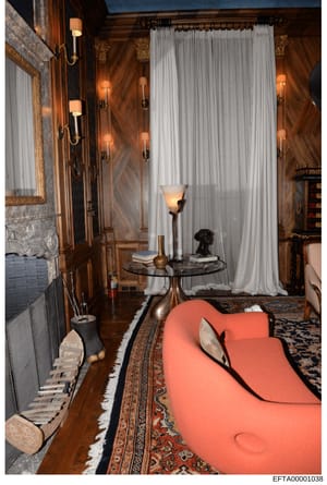 This photograph depicts a luxuriously appointed interior room featuring rich wood paneling, ornate lighting fixtures, high-end furniture including a distinctive coral/salmon-colored seating piece, and decorative elements. The room appears to be part 