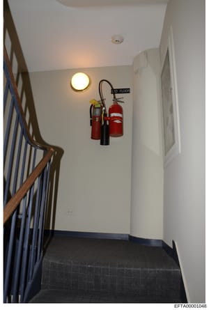 This photograph shows an interior stairwell and third-floor landing of what appears to be a residential or commercial building. The image documents the staircase structure, lighting fixtures, fire extinguishers, and the building's basic infrastructur