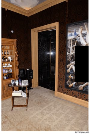 This is an evidence photograph from the Epstein investigation showing an interior room with high-end decorative elements, including dark patterned wallpaper, wooden cabinetry with glass doors containing personal care products, a black marble door fra