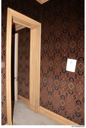 This is a photograph of an interior room space showing a wooden doorway with glass panel and decorative brown and gold patterned wallpaper. The image appears to be from an evidence collection related to one of Epstein's properties, documenting the in