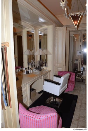 This photograph documents a high-end residential bathroom and adjoining dressing area, featuring custom cabinetry, mirrored vanity with double lamps, crystal chandeliers, and pink striped upholstered seating. The image appears to be from an evidence 
