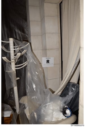 This is a forensic evidence photograph showing an interior space, likely a bathroom or utility area, containing plumbing fixtures, white PVC pipes, and multiple items wrapped in clear plastic sheeting. A marker labeled 'R' is visible for evidence doc