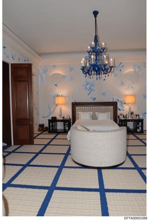 This photograph documents an opulent bedroom interior featuring blue and white Asian-inspired décor, a distinctive circular upholstered bed, ornate blue chandelier, and geometric patterned flooring. The image appears to be from one of Epstein's resid