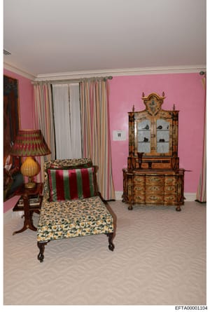 Photograph of an elaborately decorated bedroom featuring bright pink walls, antique wooden furniture including a decorative cabinet and daybed, striped curtains, and period furnishings. This appears to be documentation of an interior space, possibly 