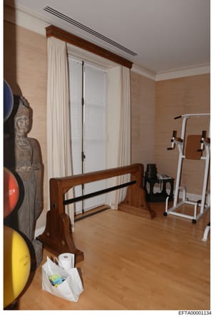 This photograph documents the interior of a residential gymnasium or exercise room, showing various fitness equipment including weight plates, exercise machines, and training apparatus. The image appears to be evidence documentation from the investig