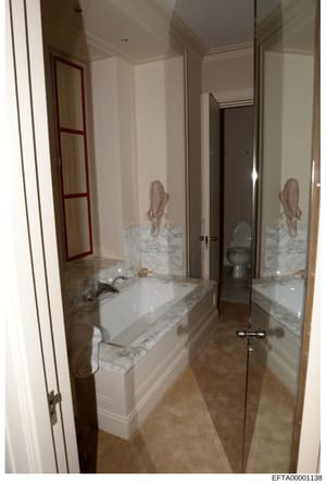 This is a photograph of an upscale bathroom interior, showing a marble-topped vanity with an integrated sink, dual mirrors with ornate frames, and marble wall accents. The room features high-end finishes typical of luxury residential properties. This