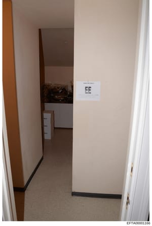 This is an evidentiary photograph of an interior room or corridor, showing a doorway with a dark wooden door frame, beige/cream colored walls, and carpeted flooring. An evidence marker labeled 'EE' is visible on the wall, indicating this image was ta