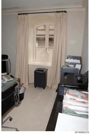 This is an evidence photograph showing an interior room with professional office equipment, including a dehumidifier, printer, stacked documents/magazines, and a computer monitor. The room features cream-colored curtains framing an arched doorway wit