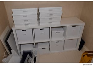 This photograph documents a storage system containing multiple white filing boxes and shelving units, likely used for organizing and storing evidence or documents related to the investigation. The boxes are labeled with small plaques, suggesting orga