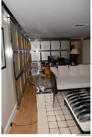 This photograph shows an interior room containing multiple computer monitors, electronic equipment, and surveillance-related technology. The room appears to be a control or monitoring center with organized display panels on the wall and various devic