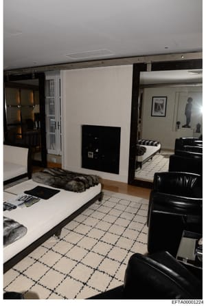 This is an evidence photograph showing the interior of a high-end residential space, featuring contemporary black and white décor with leather seating, marble flooring, and a fireplace. The image documents the property's design and layout as part of 