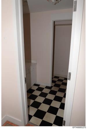 This is an evidence photograph showing the interior of what appears to be a bathroom or utility room, featuring a black and white checkered tile floor, white walls, and built-in fixtures. The photo was taken as part of the Epstein investigation docum