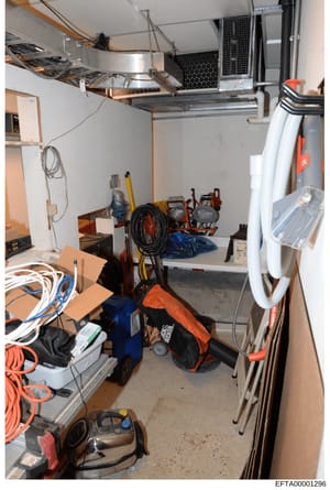 This photograph shows an organized storage space or garage containing various household and maintenance tools and equipment. The room has shelving units mounted on the walls and ceiling, storing items including power tools, extension cords, cleaning 