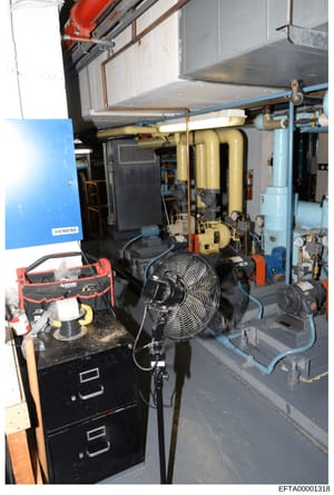 This is an evidence photograph showing the interior of a mechanical equipment room or basement utility area containing industrial HVAC, plumbing, and electrical systems. The image documents building infrastructure including a Siemens boiler unit, wat