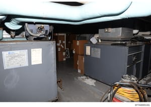 This is a photograph of a basement or mechanical room showing industrial HVAC equipment, electrical systems, and utility infrastructure. The image documents the mechanical systems in what appears to be a residential or commercial property, with visib