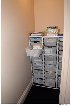 This photograph documents a storage closet containing multiple stacked plastic storage bins and boxes, with educational materials visible on top including TOEFL IBT test preparation books and 'Fire and Fury' books. The image appears to be evidence do