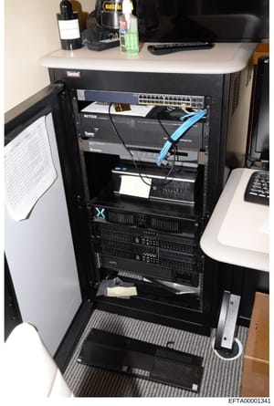 This is a photograph of a professional server rack containing networking and computing equipment, including a network switch, NITEK device, APC power distribution unit, and various other hardware components. The image appears to be documentation of I