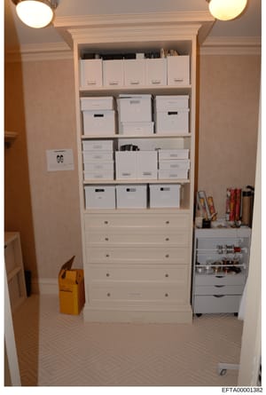 This is a photograph of a residential storage closet containing multiple white filing boxes organized on shelves, along with several pull-out drawers at the base. A yellow emergency container and craft supplies are visible on the right side. The imag