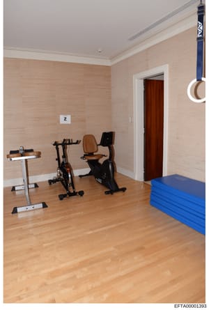 This photograph shows a private home fitness room containing multiple exercise machines including stationary bikes and a treadmill, along with blue exercise mats. The image documents the interior of what appears to be a luxury residential property an