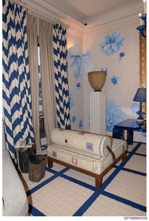 This is a photograph of an elegantly decorated interior room, likely a bedroom or dressing room, featuring blue and white color scheme decor. The room displays high-end furnishings including patterned curtains, wall murals, a pedestal with decorative