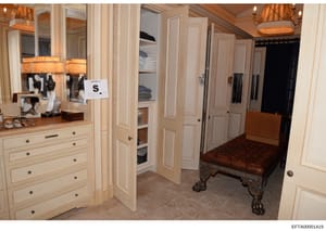 This is a photograph of an upscale residential closet and dressing room, likely from one of Jeffrey Epstein's properties. The image shows a well-appointed walk-in closet with custom cabinetry, built-in storage, elegant furnishings, and decorative lig