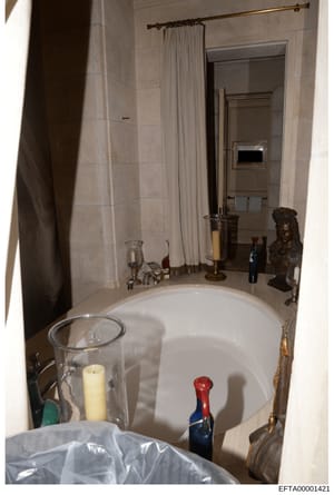 This is a photograph of an upscale bathroom interior, likely from one of Jeffrey Epstein's residences. The image shows a large soaking tub, marble walls, decorative elements including a bronze bust sculpture, candleholders, and luxury bathroom fixtur