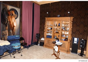 This photograph documents an interior room containing explicit artwork, personal furnishings, and various items. The room features patterned wallpaper, elaborate wooden cabinetry, and audio equipment. This image appears to be evidence documentation f
