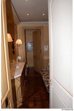 This photograph documents the interior of a luxury bathroom, showing high-end finishes including marble countertops, recessed lighting, wooden cabinetry, and decorative sconces. The image appears to be part of property documentation related to one of