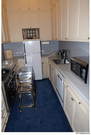 This is a photograph of a residential kitchen interior, showing appliances, cabinetry, countertops, and furnishings. The image appears to be documentation of property conditions, possibly from a residence associated with the investigation. The kitche