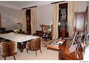 This is a photograph of an ornately decorated interior room, likely part of a residential property, featuring high-end furnishings including leopard-patterned upholstered chairs, wooden furniture, cream-colored curtains, and various decorative object