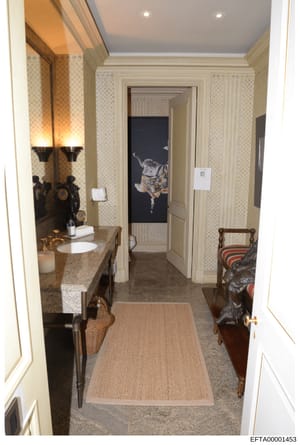 This photograph documents a high-end bathroom interior featuring marble countertops, dual sinks, decorative sconces, and multiple doorways leading to adjacent rooms. The image appears to be part of property documentation, likely from one of Epstein's