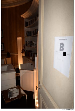 This is an evidence photograph showing the interior of a room with distinctive curved architectural elements, built-in bookshelves, and warm lighting. A label marked 'B' is visible on the wall, suggesting this is a documented room from a property ins