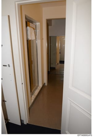 This is an evidence photograph showing an interior hallway and bathroom space with beige/tan walls, white trim, and a glass-enclosed shower with white towels. The image appears to be documentation of a residential property, likely taken as part of th