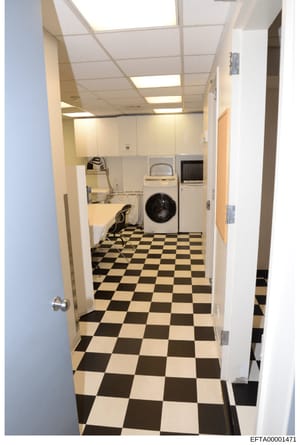 This is a photograph of a residential laundry room featuring standard household appliances and furnishings. The room displays a black and white checkered floor tile pattern, white cabinetry, a front-loading washing machine, dryer, and various utility