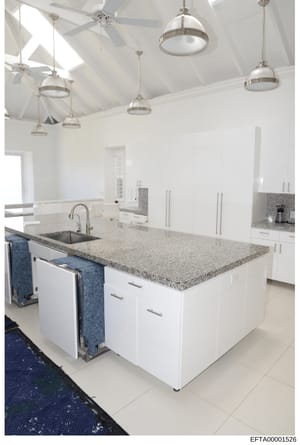 This is a photograph of a contemporary kitchen interior, likely from one of Epstein's properties. The image shows a large, well-appointed kitchen space with high vaulted ceilings, modern fixtures, and luxury finishes. The photo appears to have been t