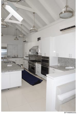 This is a photograph of a contemporary kitchen space, likely from one of Jeffrey Epstein's properties. The image shows a recently renovated or upscale kitchen featuring white cabinetry, granite countertops, stainless steel professional-grade applianc
