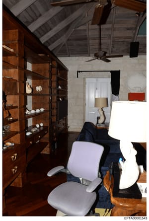 This is a photograph of an interior room space, likely an attic or upper floor area of a property, showing architectural details and furnishings. The room features vaulted ceilings with exposed beam work, built-in wooden shelving units displaying dec