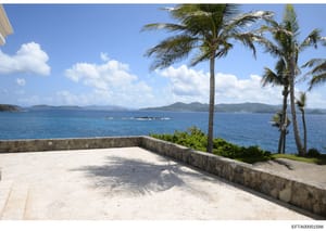 This photograph shows a spacious white stone terrace or deck overlooking a turquoise Caribbean sea with multiple islands visible on the horizon. The image appears to be documentation of a property, likely from one of Epstein's residences in the U.S. 