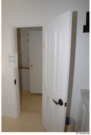 This is a photograph of an interior hallway with white walls and doors, including a bathroom entrance marked with a handwritten sign reading 'Please do not Use this BATHROOM!!!!' This appears to be evidence documentation from a property search or ins