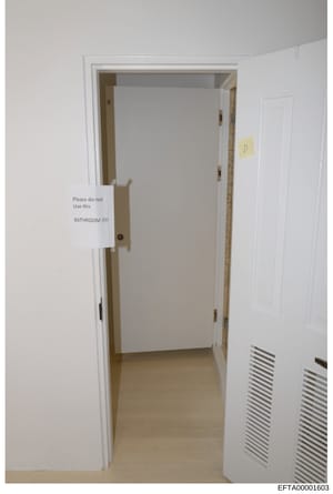 This is an evidence photograph from the investigation showing an interior doorway to a bathroom with a white sign attached to the door reading 'Please do not Use this BATHROOM!!!!' in handwritten text. A yellow label marked 'D' is visible on an adjac