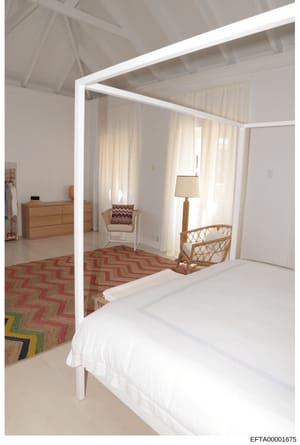 This is a professional interior design rendering or architectural visualization of an upscale bedroom featuring a white four-poster canopy bed, wooden furniture, and geometric patterned area rugs in red and natural tones. The image appears to be a de