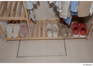 This is an evidence photograph showing the interior of a closet or entryway space containing a wooden shoe rack with multiple pairs of shoes in various styles and colors, along with hanging clothing visible above. The image documents the living space